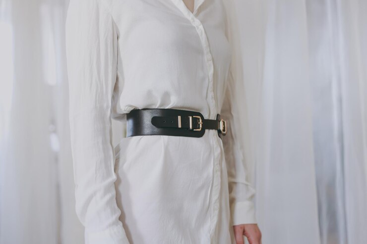 Young girl in a white office shirt trying on a leather belt