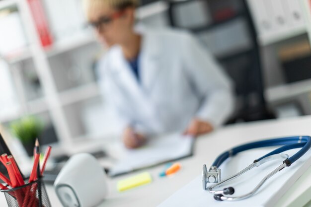 A young girl in a white robe sitting at the table with phonendoscope