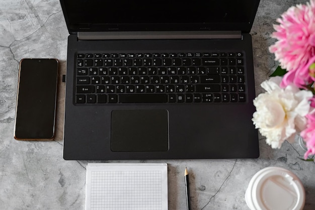 A young girl in a white shirt is working on a laptop with a coffee mug remote work and education