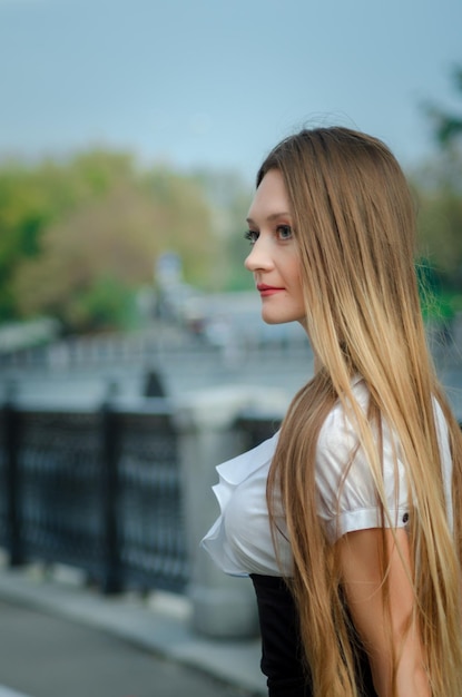 A young girl in a white shirt poses in the city