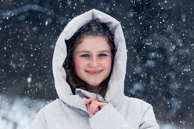 降雪時の冬の森の少女。冬の森の若い幸せな女の子の肖像画