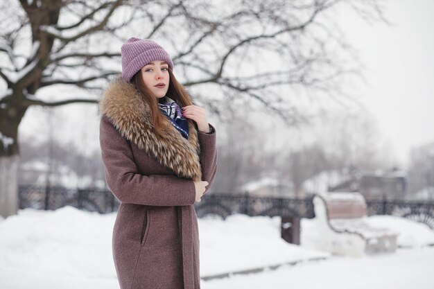 A young girl in a winter park on a walk. Christmas holidays in the winter forest. Girl enjoys winter in the park.