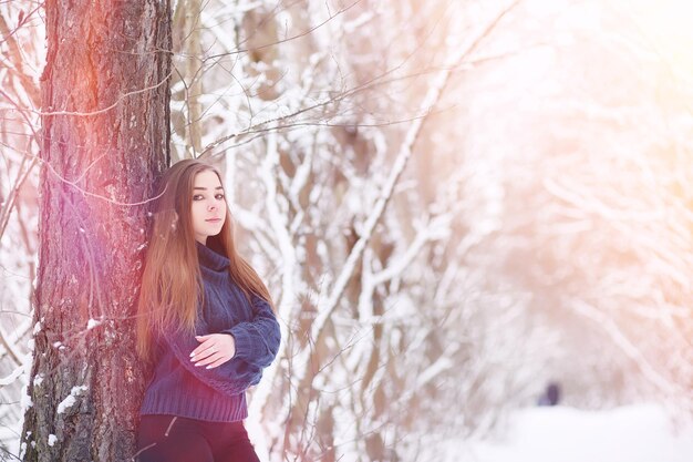 A young girl in a winter park on a walk. Christmas holidays in the winter forest. Girl enjoys winter in the park.