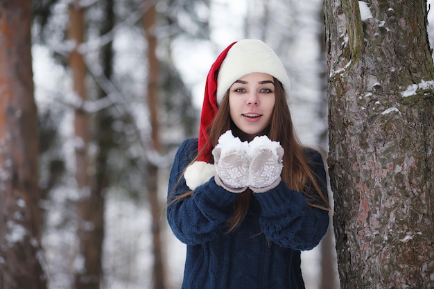 散歩の冬の公園で若い女の子。冬の森のクリスマス休暇。女の子は公園で冬を楽しんでいます。