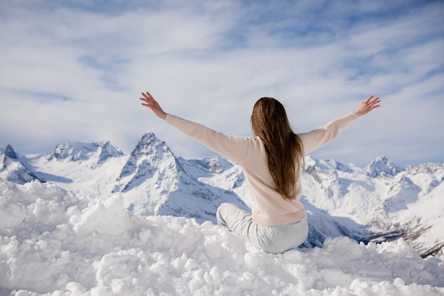 young girl in a winter suit looking at the mountains