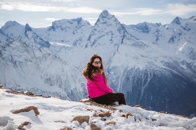 young girl in a winter suit looking at the mountains