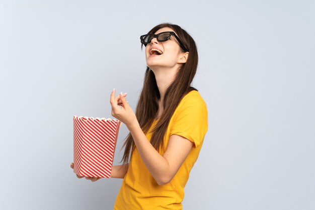 Young girl with 3d glasses and holding a big bucket of popcorns