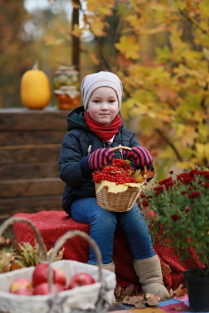 写真 秋の公園でガマズミ属の木のバスケットを持つ少女