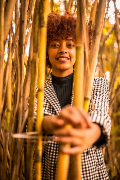 Young girl with afro hair of Dominican nationality photographed inside bamboos holding on