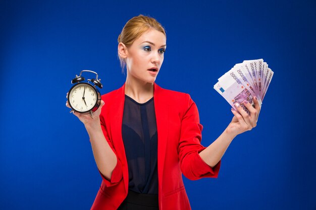 Young girl with an alarm clock and money