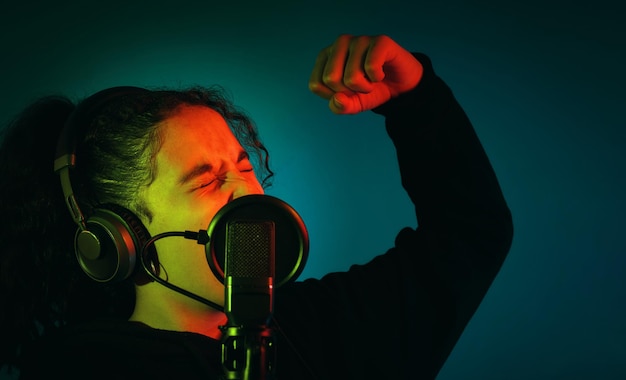 Photo young girl with an arm raised and her eyes closed while she39s singing with headphones and a microphone indoors with copy space