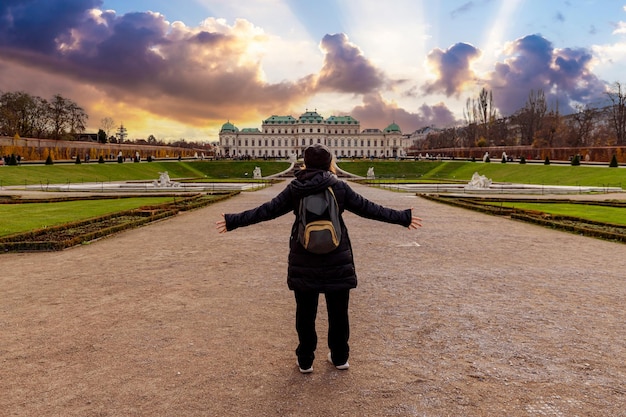 Photo young girl with arms outstretched in front of schloss belvedere in vienna