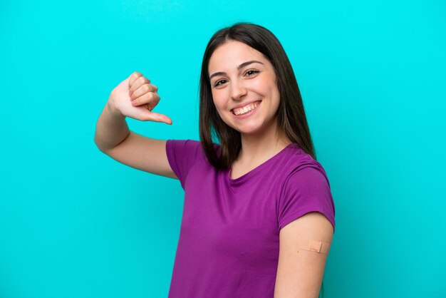 Young girl with bandaids isolated on blue background proud and selfsatisfied