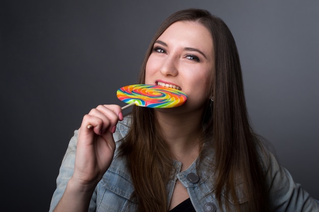 Photo young girl with big lollipop candy on gray background