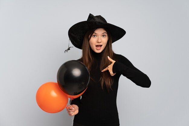 Young girl with black hat and black dress holding ballons