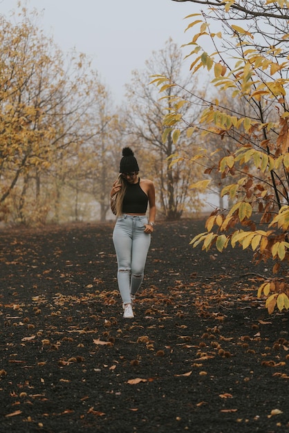 Young girl with black wool cap in field with background of orange trees in autumn with very cold