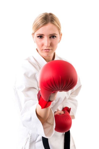 Young girl with blonde hair in karate kimono and boxing gloves