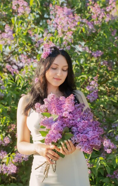 Young girl with blooming lilac in sunlight