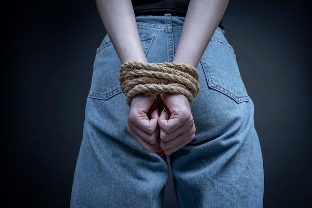 Young girl with bound hands on black background close up