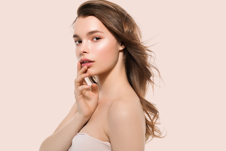 Photo young girl with care beautiful healthy clean skin and hand touching face. color background. pink