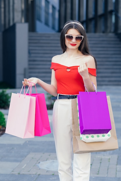 Young Girl with colorful shopping bags walking around the city after shopping. Consumerism, purchases, shopping, lifestyle concept.