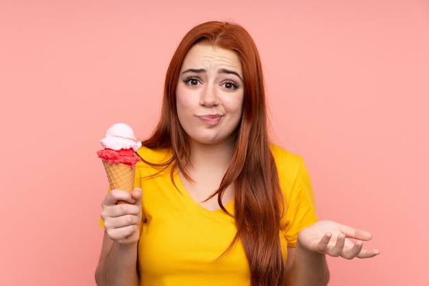 Young girl with a cornet ice cream over isolated wall making doubts gesture while lifting the shoulders