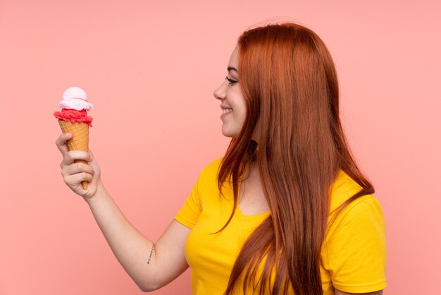 Young girl with a cornet ice cream over isolated wall with happy expression