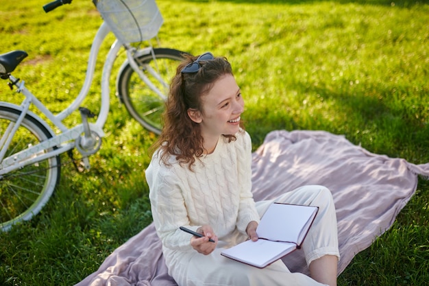 A young girl with a diary in hands thinking and making notes