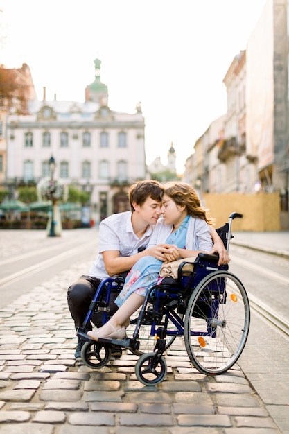 Giovane ragazza con malattia su una sedia a rotelle e il suo uomo adorabile
