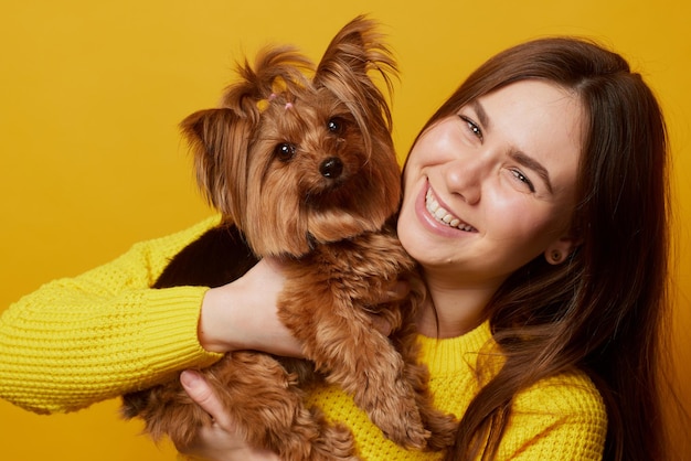 Young girl with a dog Yorkshire terrier on a yellow clean background