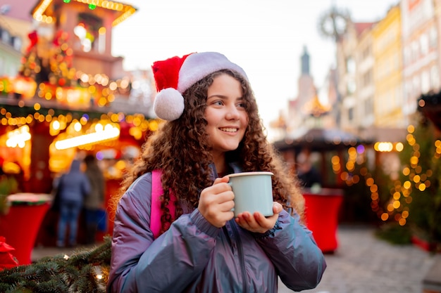 Ragazza giovane con drink sul mercatino di natale a wroclaw in polonia