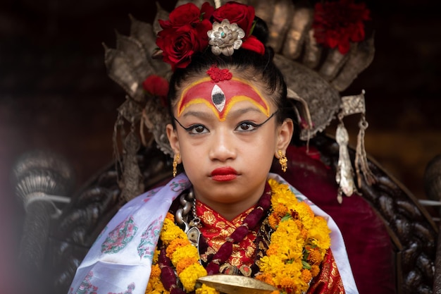 A young girl with a face painted in red and gold is posing for a photo.