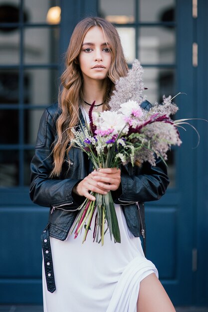 Foto ragazza con fiori in cappello estivo in posa sul campo