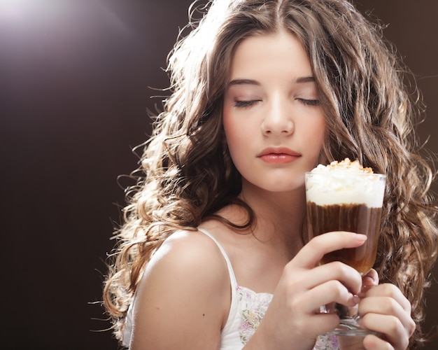 Young girl with glass of coffee witn whipped cream