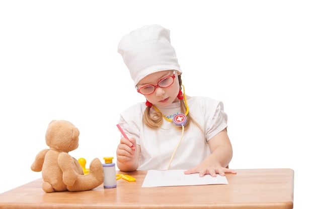 Young girl with glasses plays in the doctor as a mom and treats toys