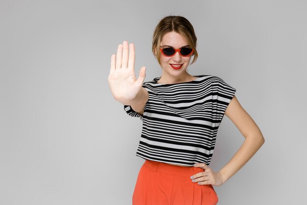 Young girl with glasses shows a hand sign stop.