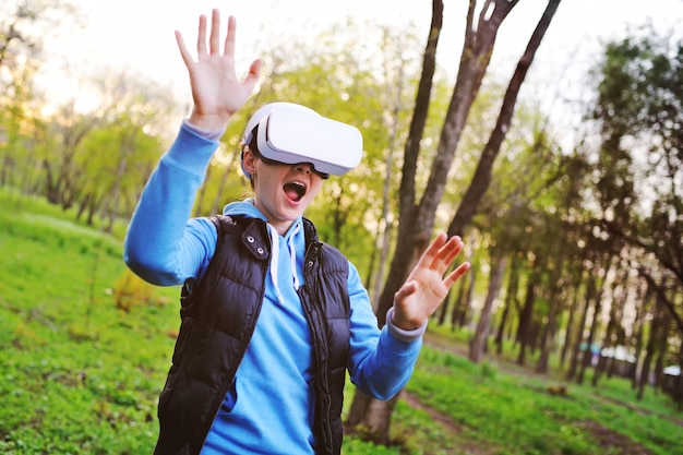 Молодая девушка в очках виртуальной реальности на поверхности зелени и парка