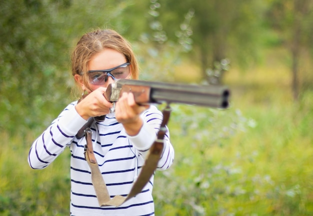 Photo a young girl with a gun for trap shooting and shooting glasses aiming at a target short depth of field focus on the face