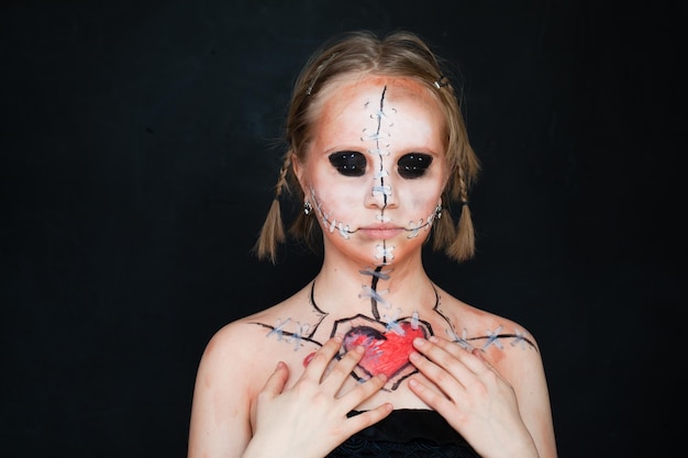 Photo young girl with halloween makeup nad broken love heart