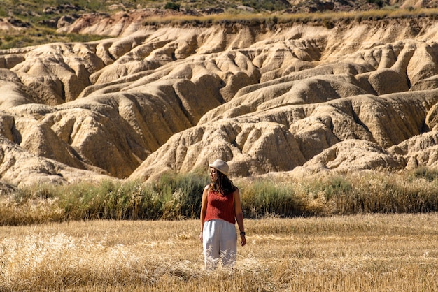 Bardenas Reales Navarra에서 여행하는 모자 갈색 셔츠와 흰색 바지를 입은 어린 소녀