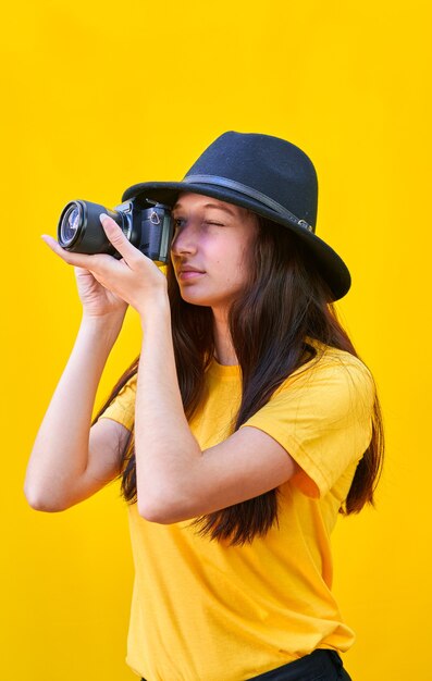 Giovane ragazza con il cappello di scattare una foto nella giusta direzione