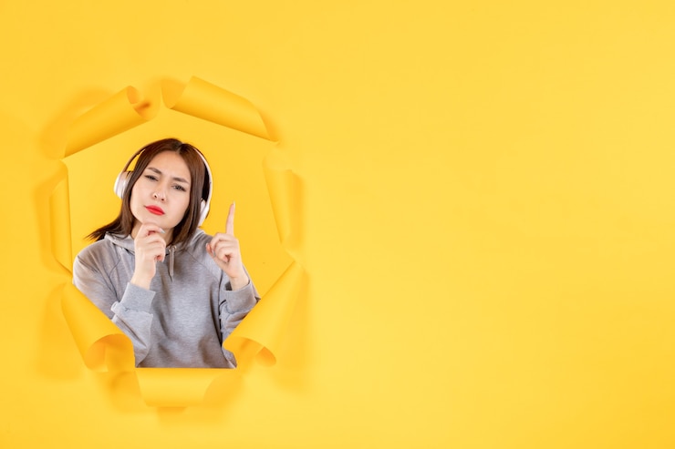 Photo 노란 종이 배경 오디오 초음파 소리에 헤드폰을 끼고 있는 어린 소녀