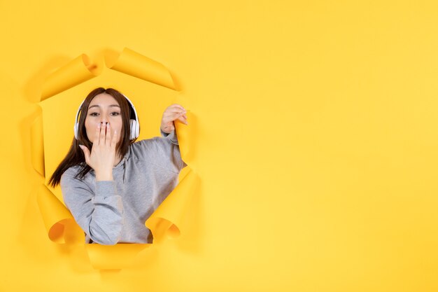 young girl with headphones on yellow paper background music audio sound