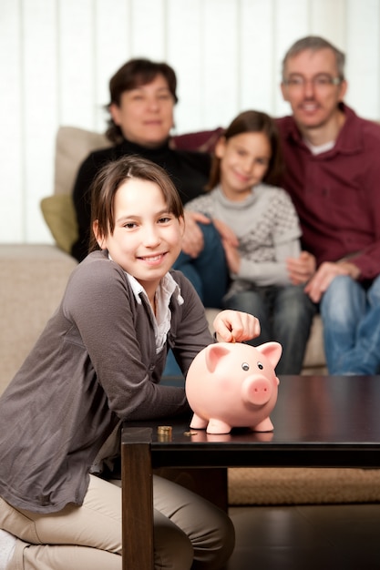 young girl with her parents and daughter saving money on a piggy bank