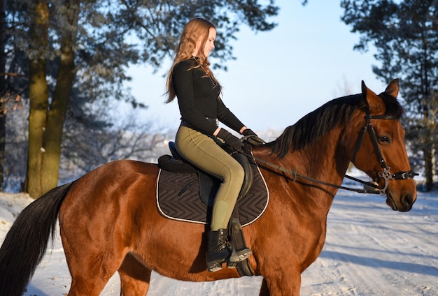 Young girl with horse on winter forest road.