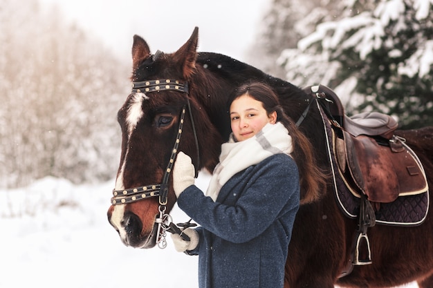 森の中で冬に馬を持つ少女。自然や動物とのコミュニケーション