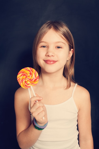 Young girl with lollipop on background