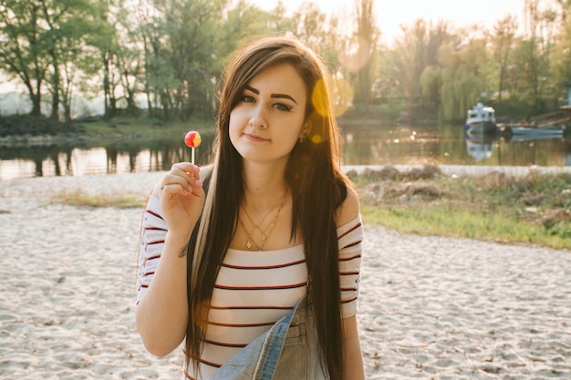 Young girl with long hair on the beach during sunset. Sun glare.