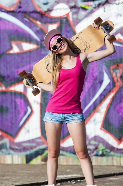 Young girl with longboard posing outdoors