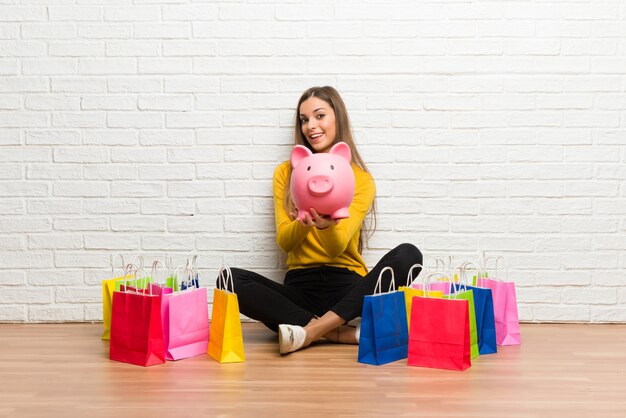 Young girl with lot of shopping bags holding a piggybank